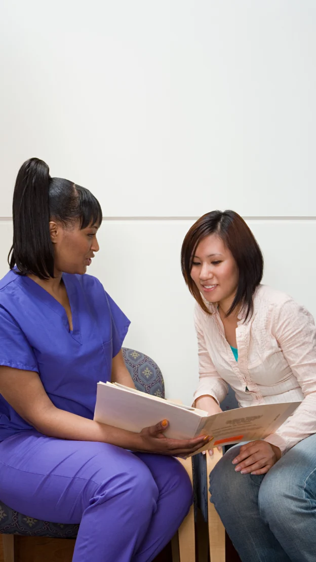 two women with paperwork in a conversation.