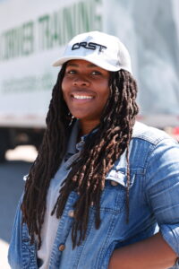 Young female student smiling while standing in front of a tractor-trailer